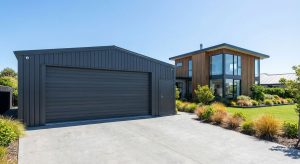Modern prefabricated steel garage featuring durable metal cladding, wide-span roller door access, and low-maintenance exterior finish, providing secure vehicle storage and scalable expansion potential for residential or light commercial applications.