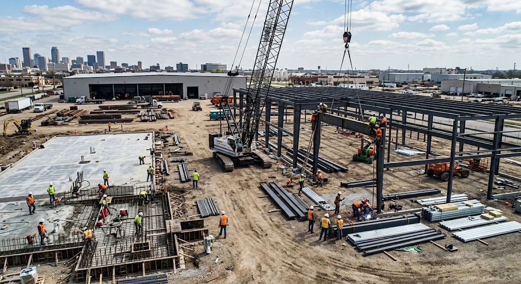 "Workers assembling steel framework on a showroom site, illustrating timeline strategies to speed up construction."