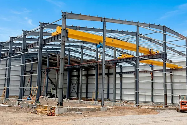 Africa steel structure workshop project under construction with steel columns, roof beams, wall panels, and overhead crane system installation.