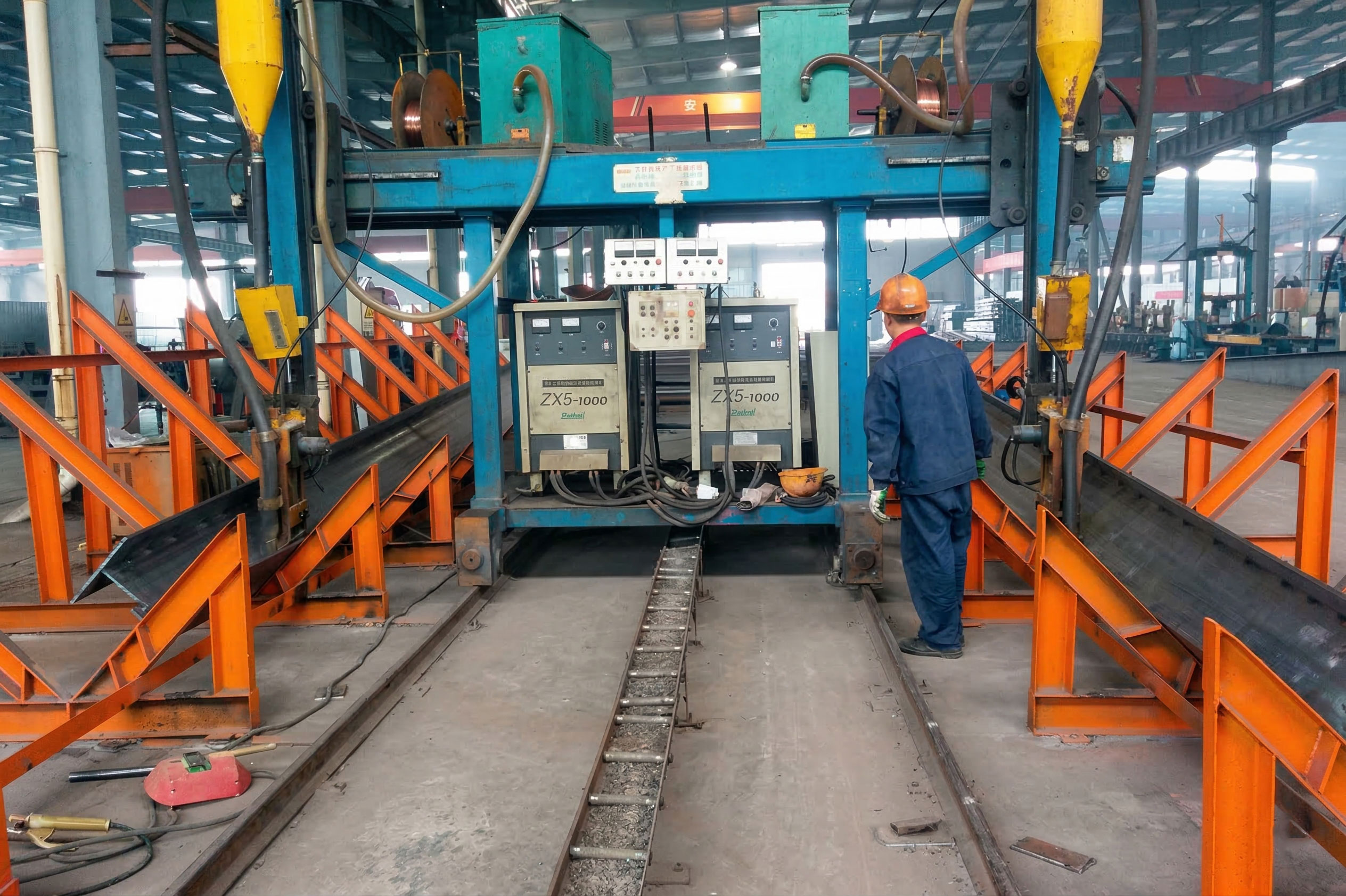 Automatic welding line joining H-section steel members for warehouse frames with twin welding heads and an operator.