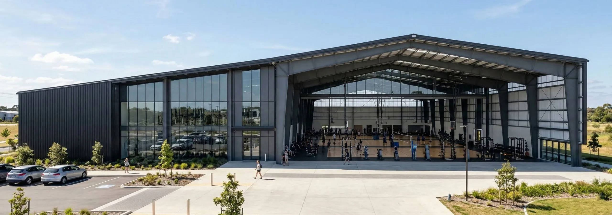 Steel sports facility with basketball courts, weight stations, glass frontage and perimeter columns.