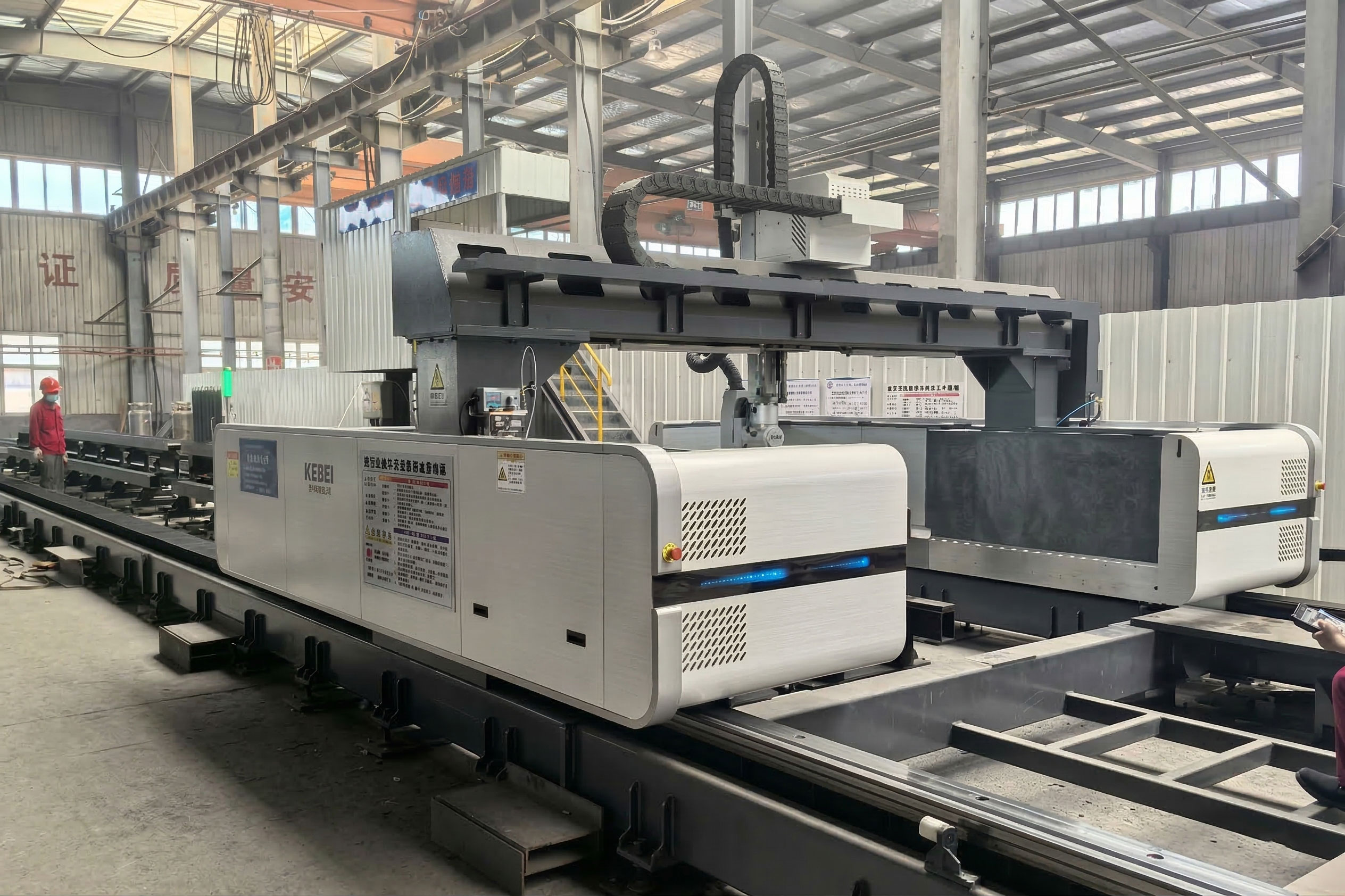 CNC laser cutting machine processing a structural steel beam for warehouse fabrication in an automated workshop.
