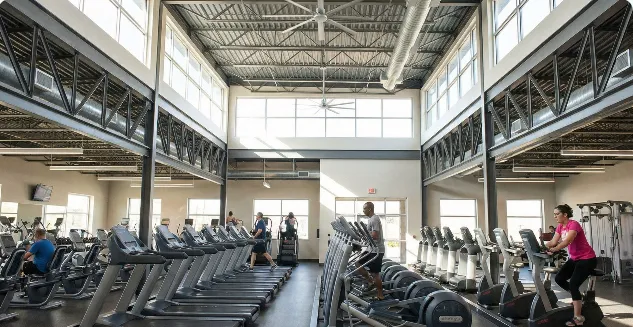Elevated side decks frame a bright conditioning floor equipped with parallel running and cycling stations.