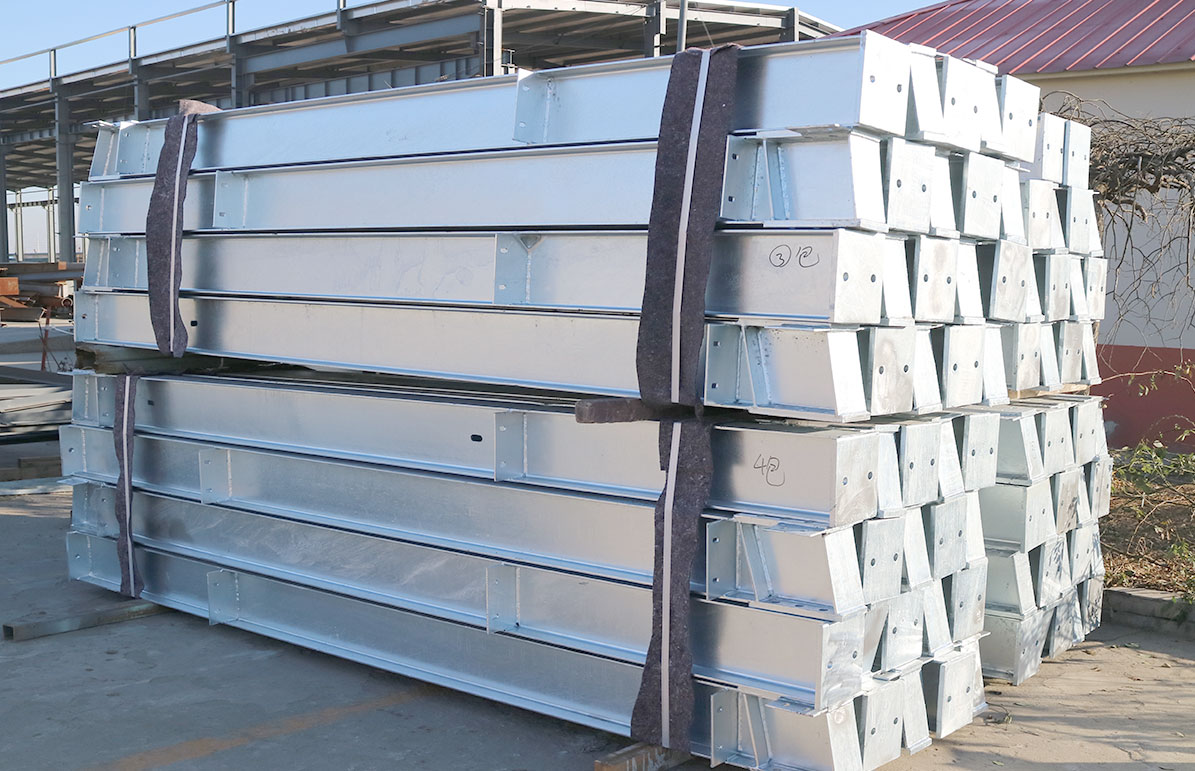 Hot-dip galvanized H-section steel members with drilled end plates and welded brackets bundled for structural frame assembly.