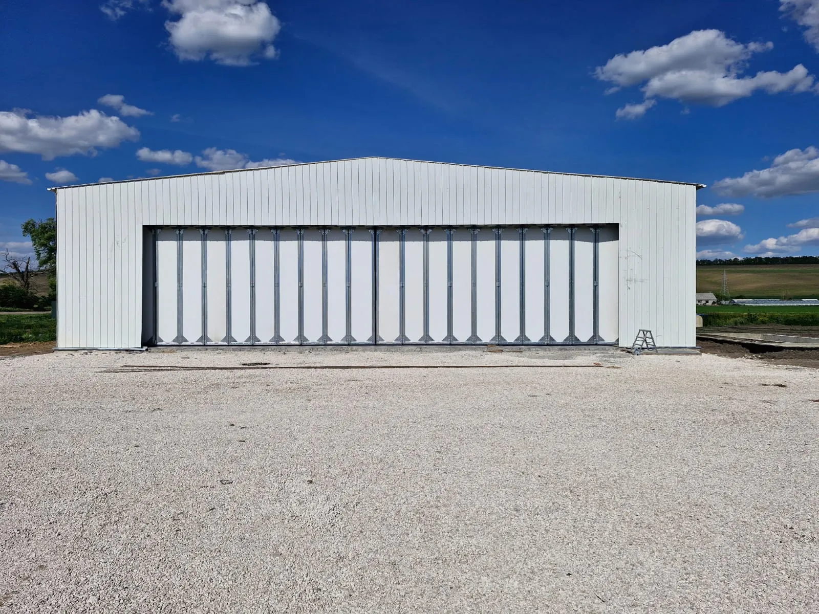 Completed 600 m² steel aircraft hangar in Moldova with white cladding and a nearly 20 m multi-panel sliding door.