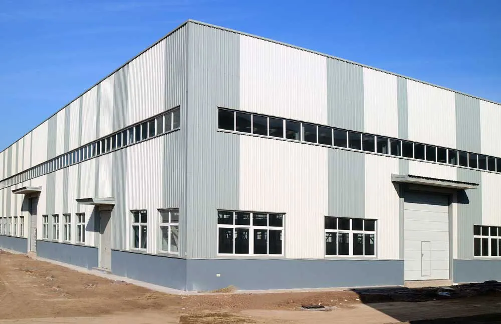 Exterior view of a prefabricated steel structure building used for factory production, with metal wall panels, windows, and large industrial doors.