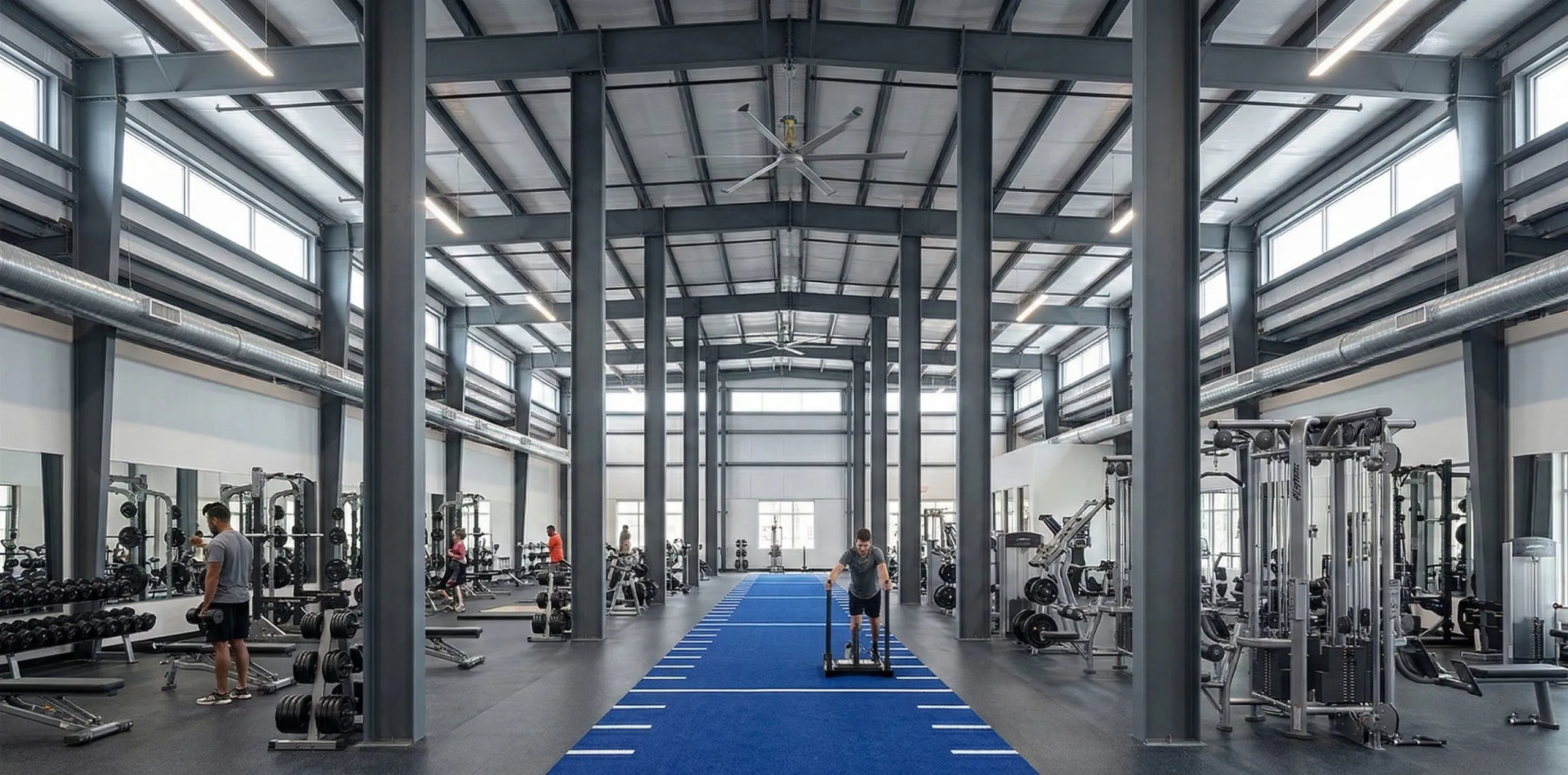 Steel building gym interior with closely spaced columns, strength equipment and a central sled training track