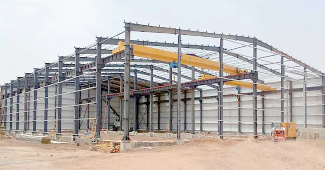 Steel frame workshop installation with portal steel structure, overhead crane, roof purlins, wall panels, and industrial workspace.