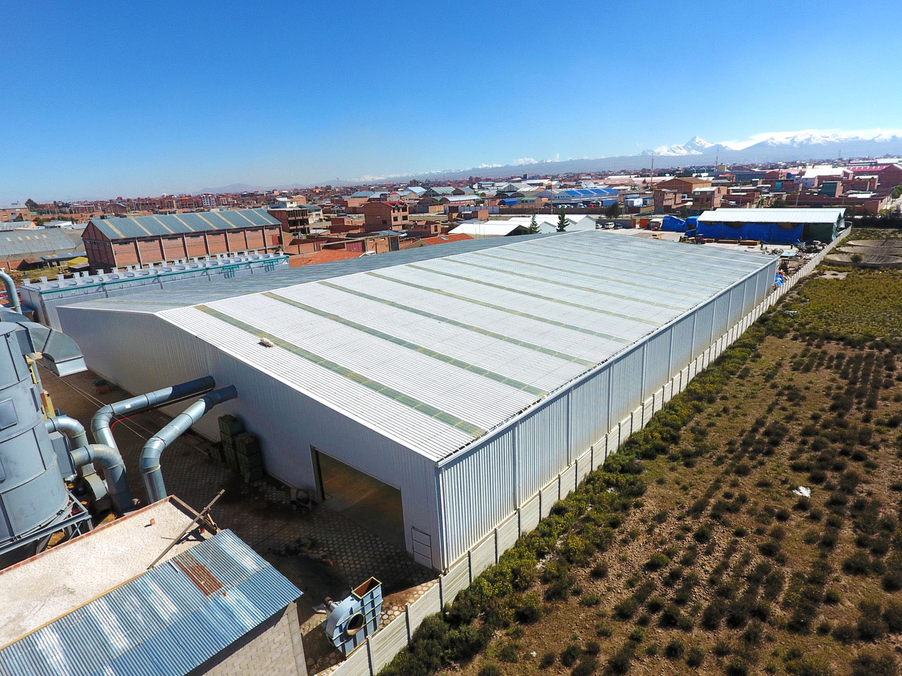 Steel structure factory building project in Bolivia with metal cladding, roof skylights, and exterior ventilation equipment.
