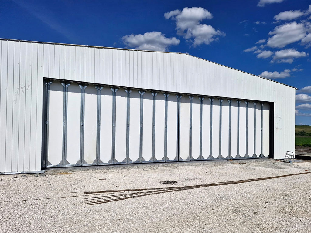 Steel structure hangar project in Moldova with metal wall cladding and a wide multi-panel door for large equipment access.