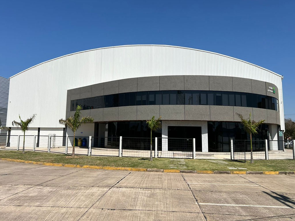Steel structure industrial building project in Bolivia with a curved roof, metal wall cladding, and two-storey glazed office frontage.