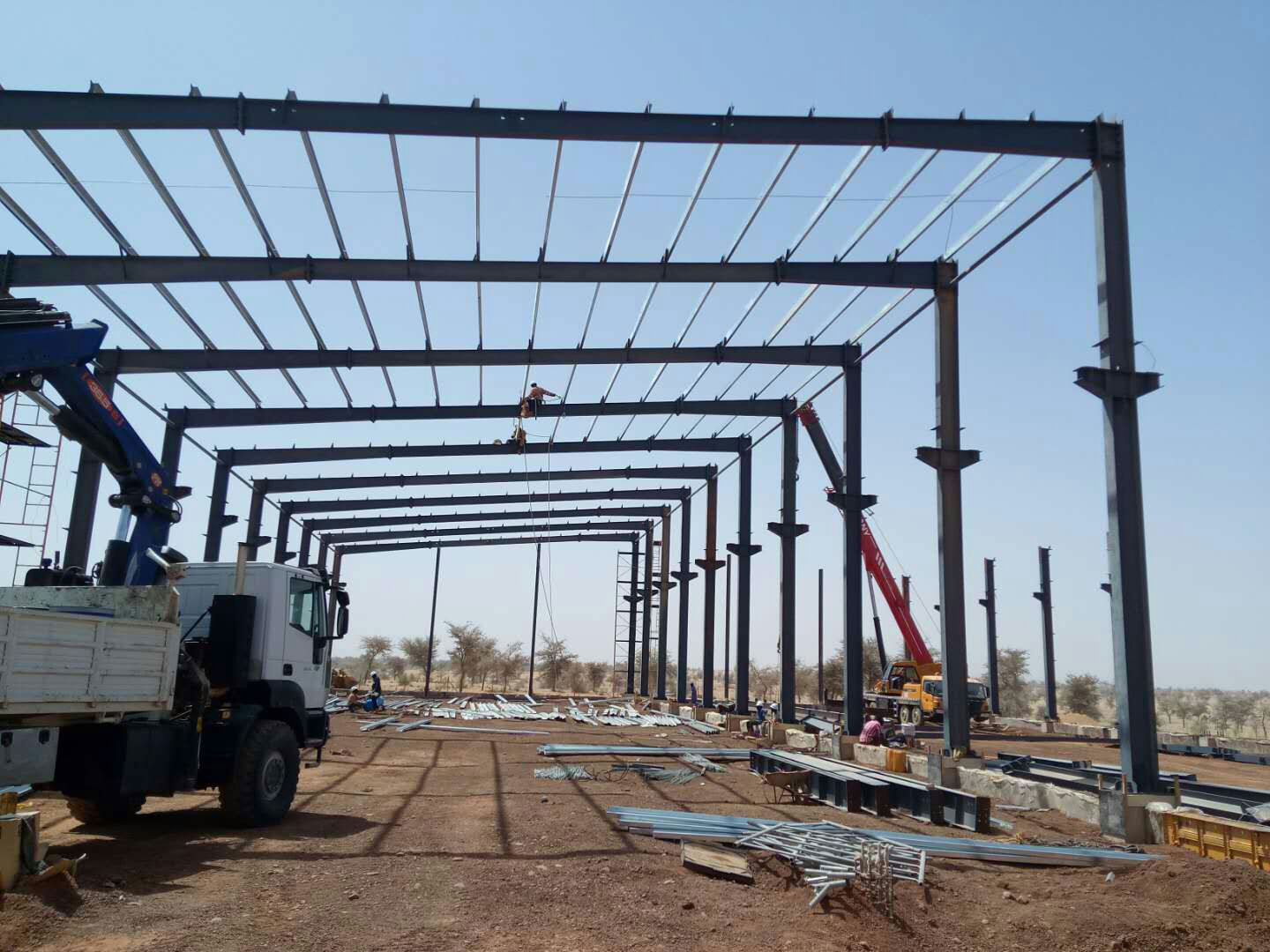 Steel structure industrial building project in Niger with portal frames, roof purlins, and cranes during frame erection.