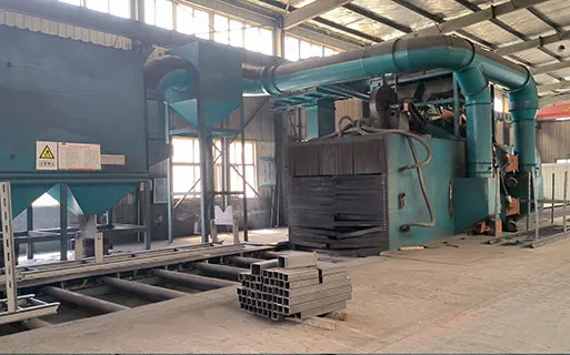 Shot blasting equipment cleaning steel components for high-quality steel structure building production before painting and corrosion protection.