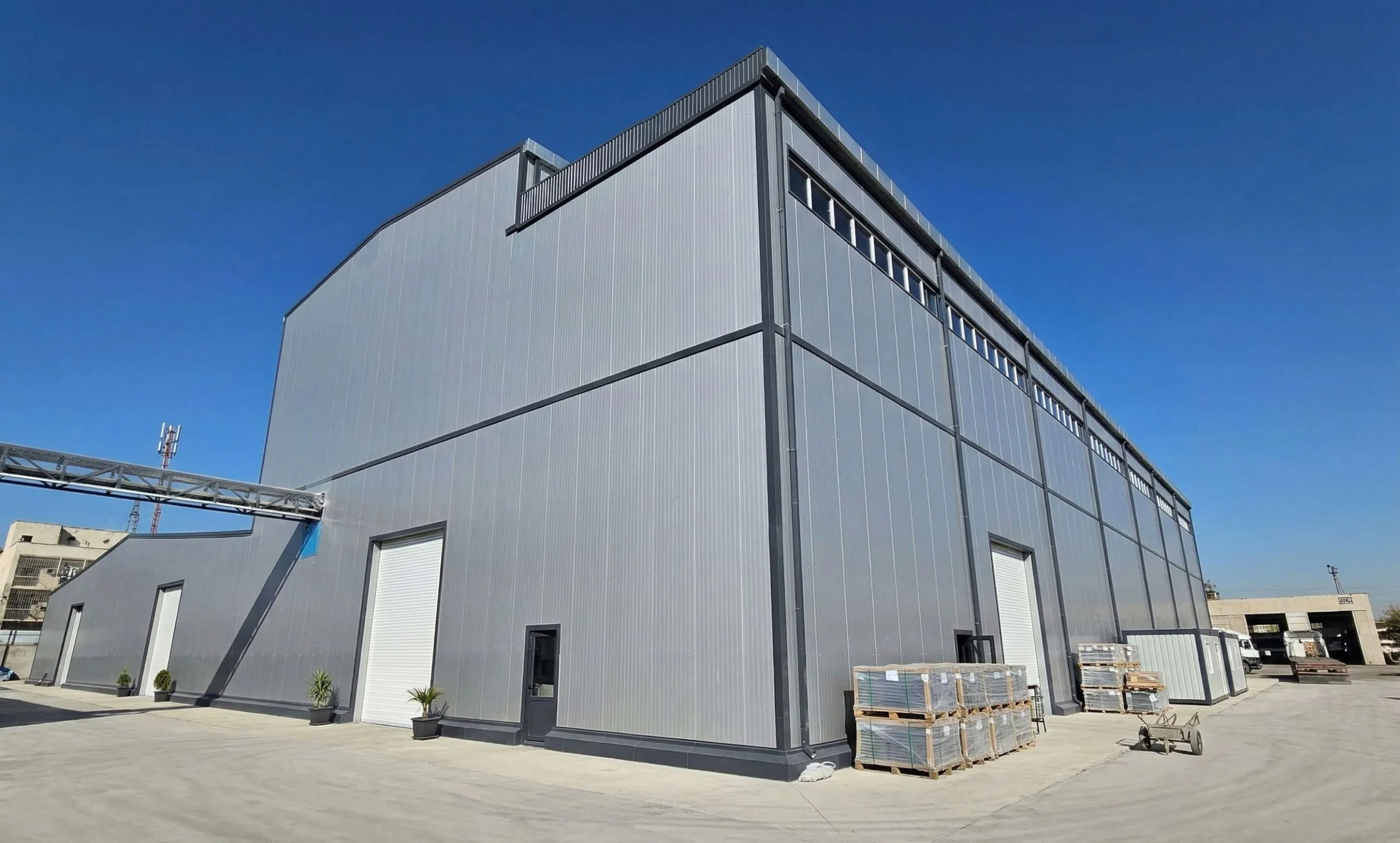 Completed steel structure textile factory in Uzbekistan with metal cladding, high-level windows and roller doors.
