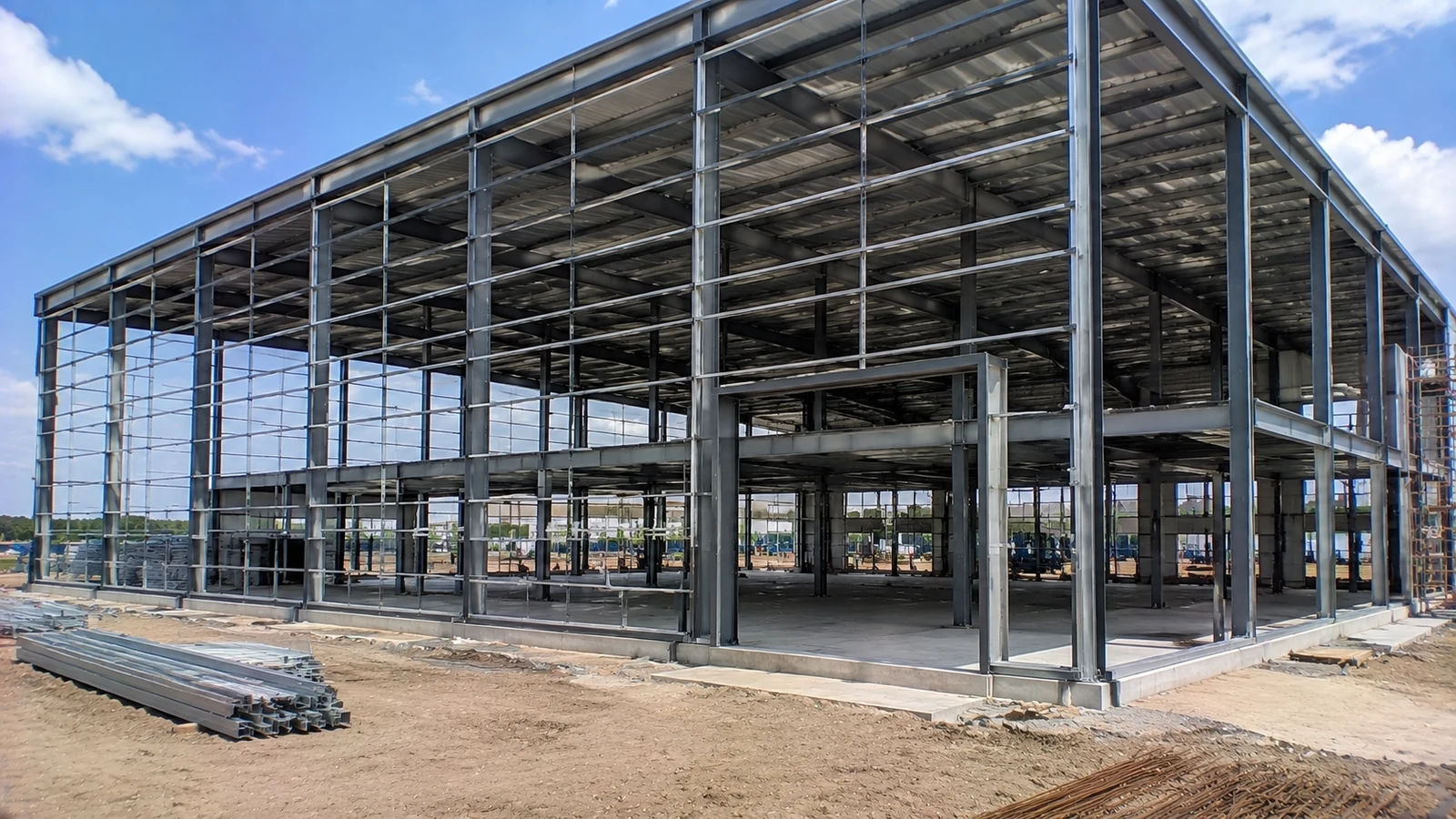 A steel frame and facade support grid define openings across an unfinished showroom.