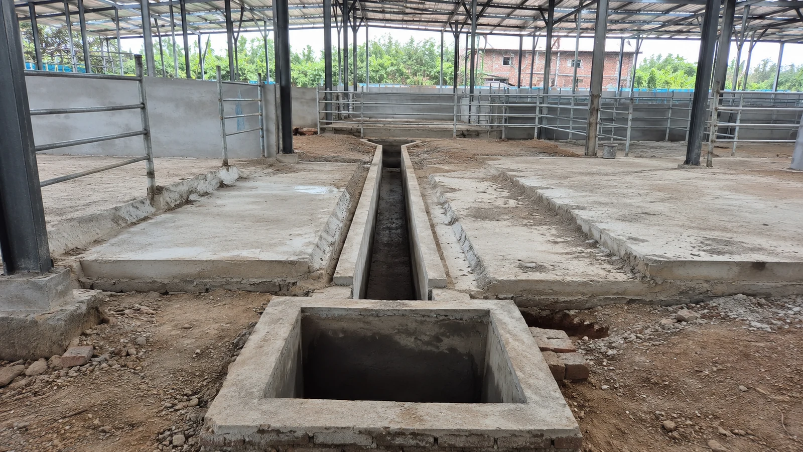 Open manure channel and inspection pit before floor completion inside a steel pig house.