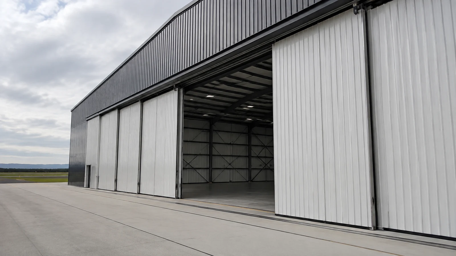 Large sliding door panels open across a steel aircraft hangar with clear apron access.