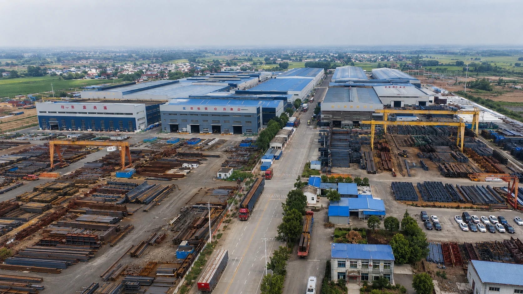 Aerial view of a steel structure factory with workshops, steel stockyards, cranes, roads and material storage areas.