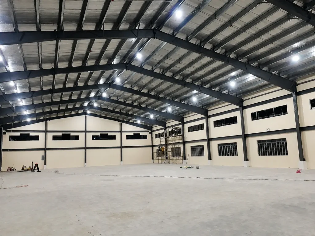 Completed interior of a Philippines steel warehouse with portal frames, insulated walls, bright lighting, and open floor.