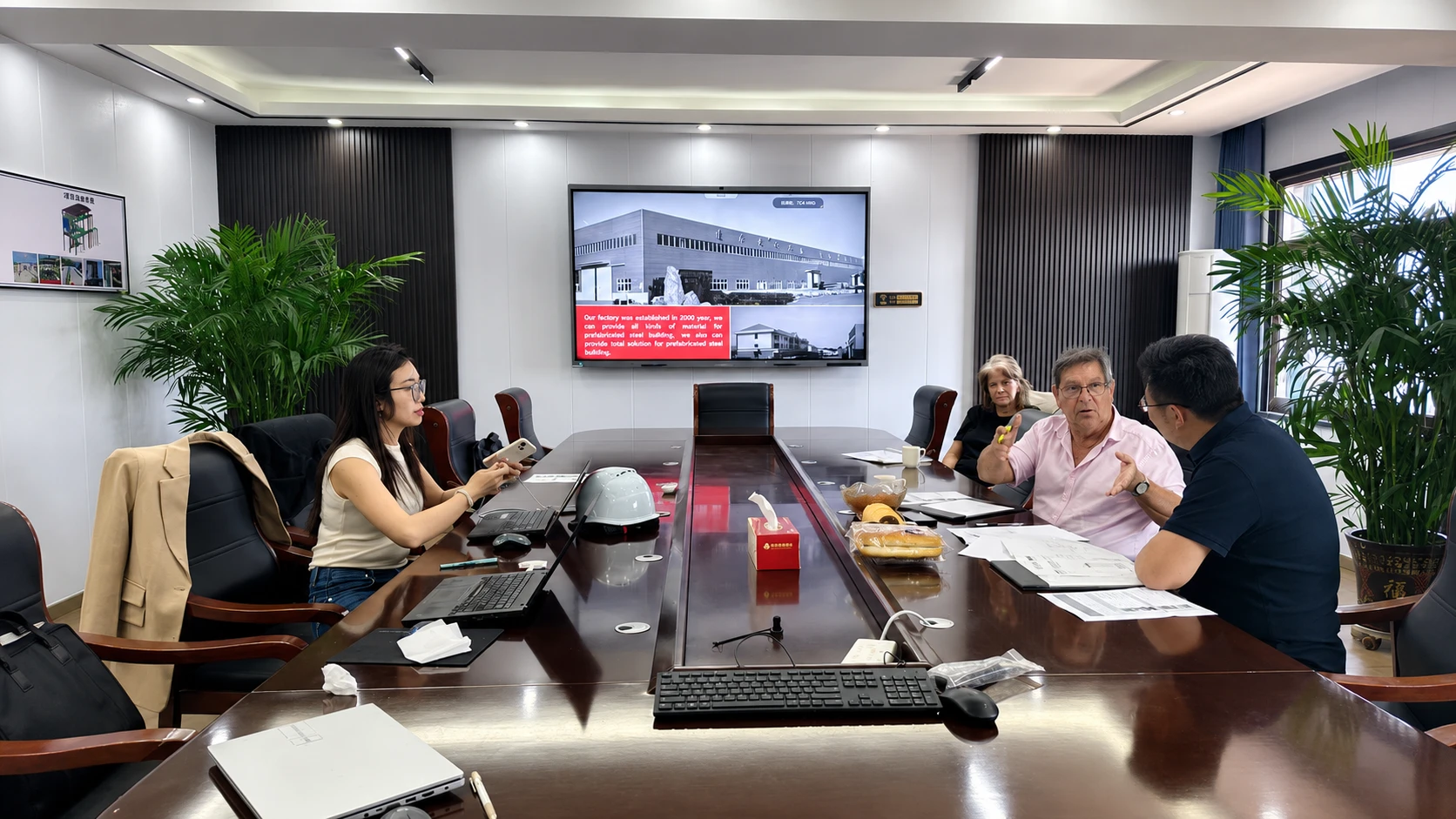International clients discussing steel structure project drawings and requirements with the supplier team in a meeting room.