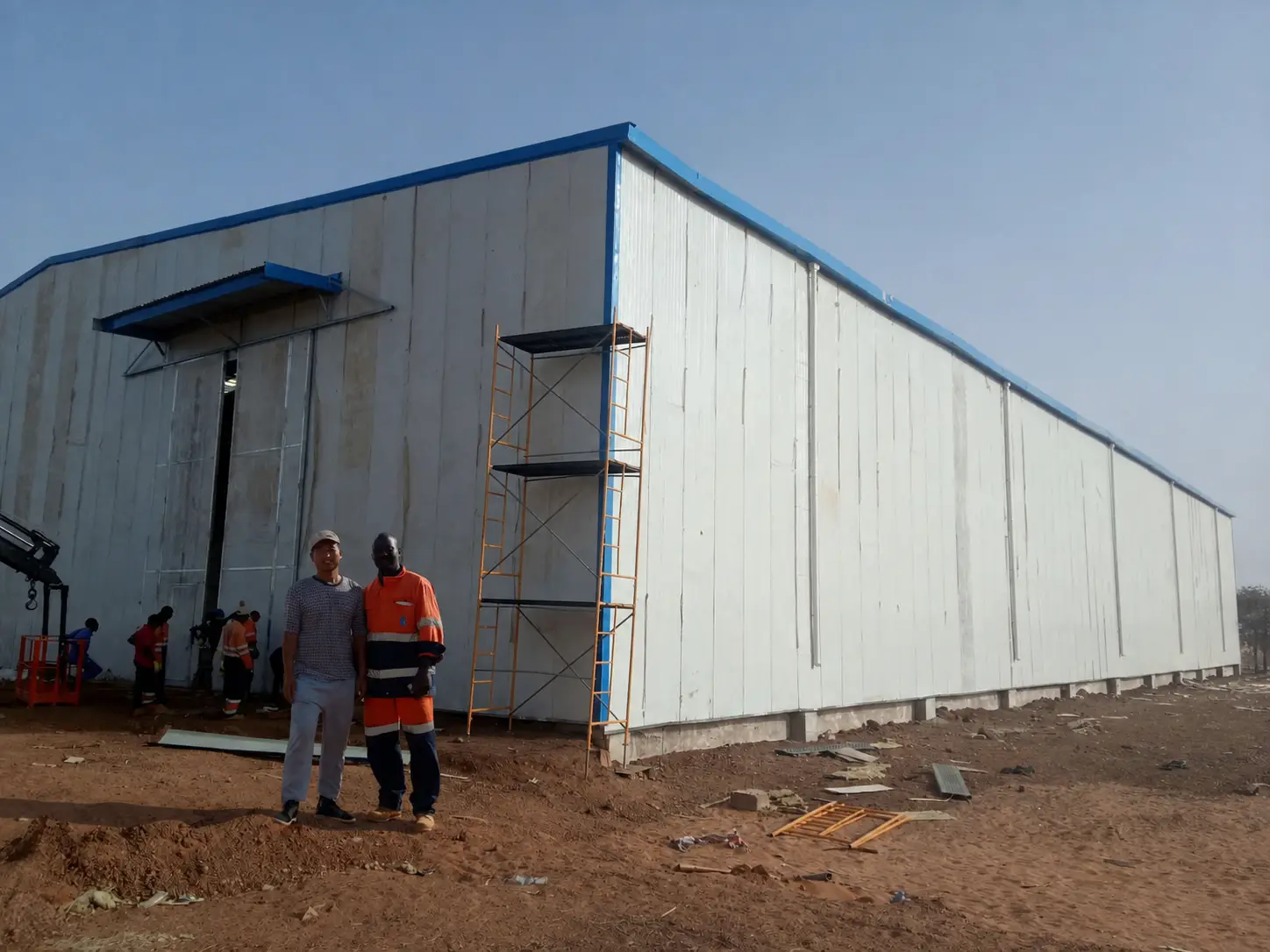 Exterior of Niger steel structure warehouse with completed wall panels and project personnel on site