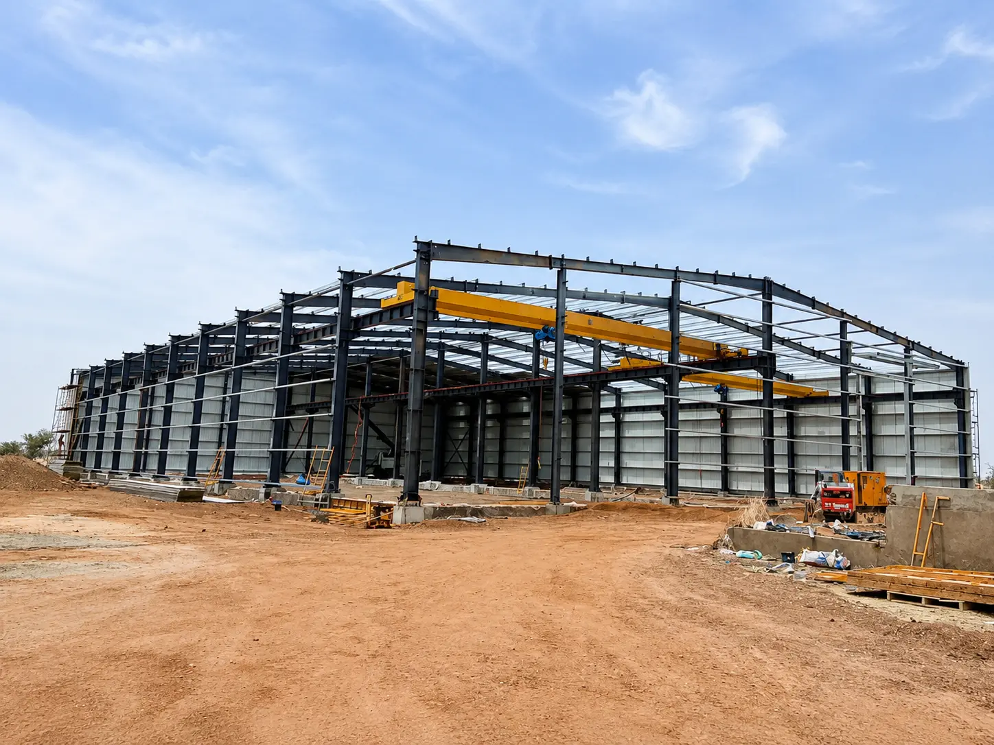 Niger steel warehouse under construction with portal frames, wall cladding, and overhead cranes installed.