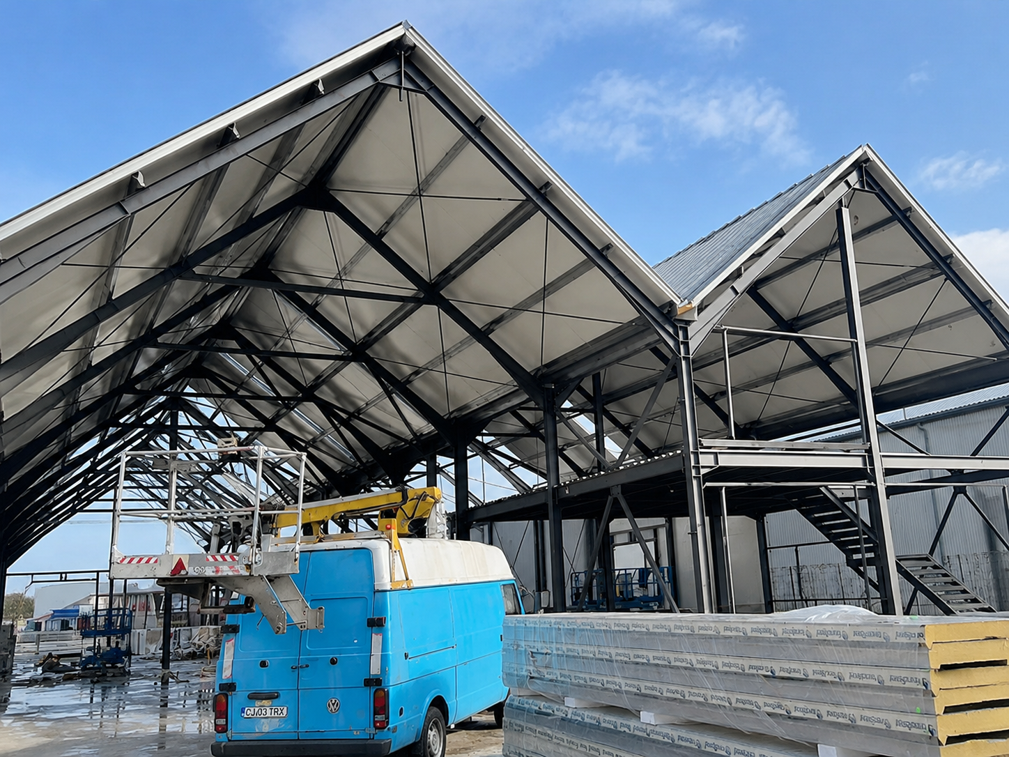 Storage and office warehouse under construction in Romania with steel roof trusses, mezzanine framing and insulated panels.