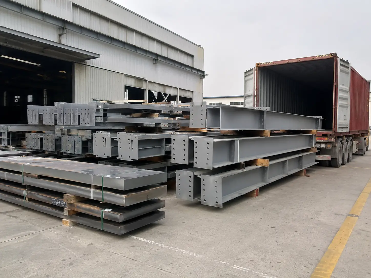 Steel structure components staged beside a container for loading and overseas shipment