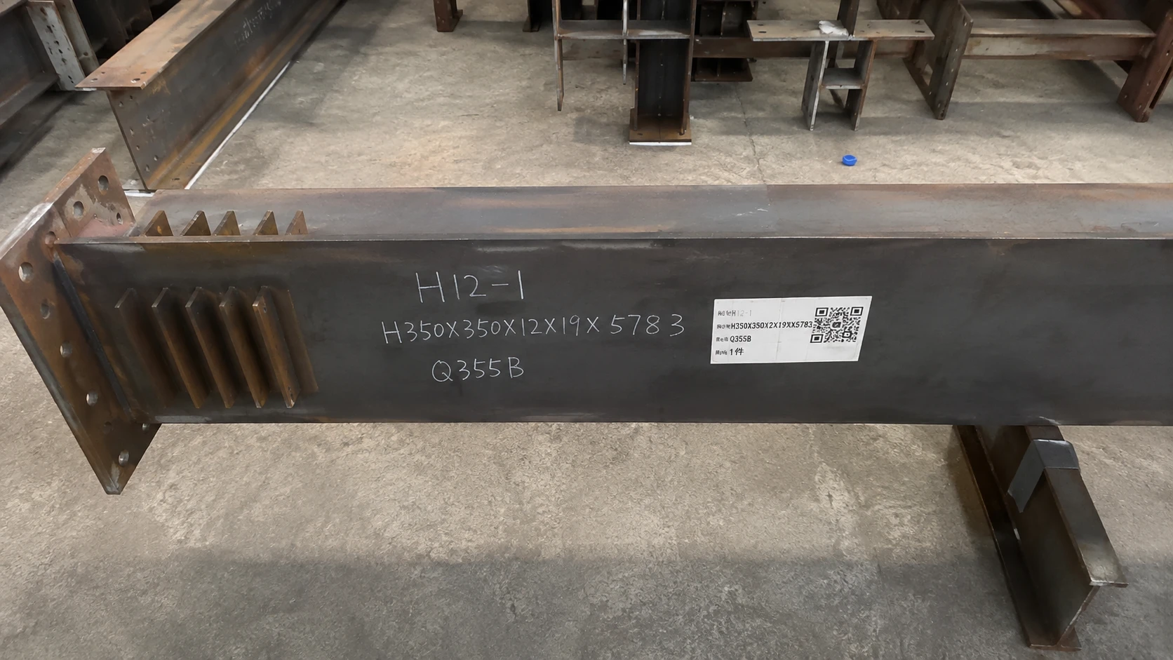 Q355B steel beam marked with component ID, section size and QR code for fabrication tracking and traceability.