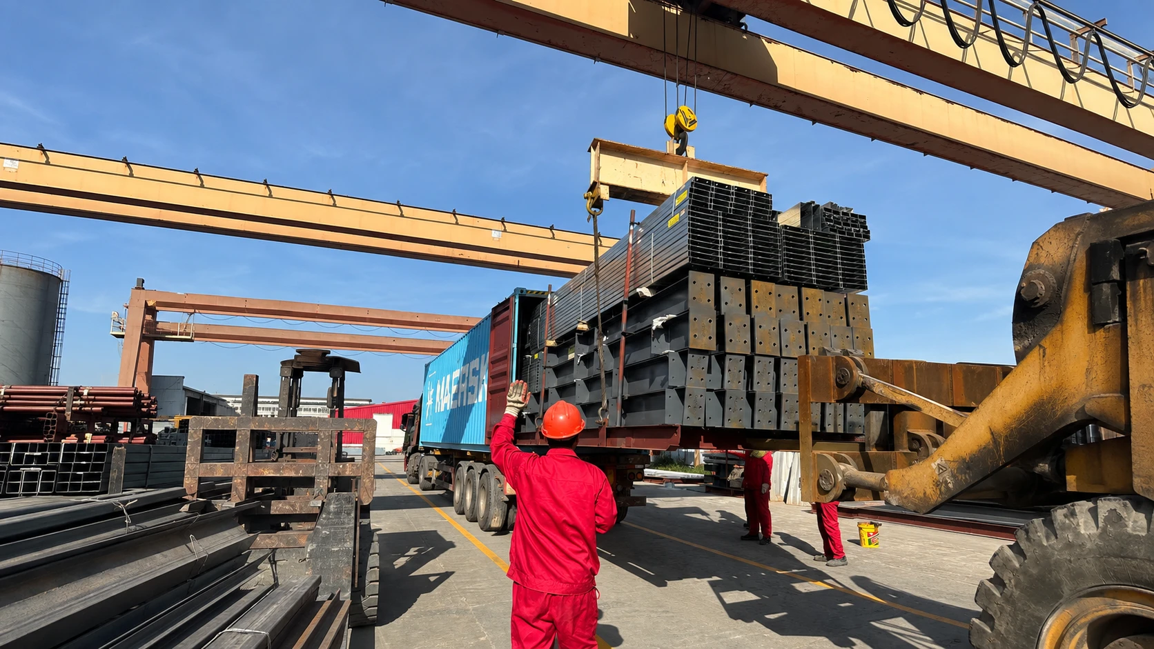 Workers loading fabricated steel structure components into a container for secure packing and international shipment.
