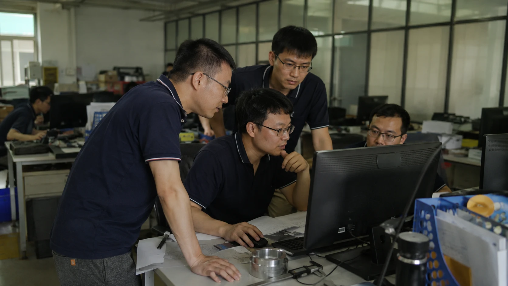 Steel structure engineering team reviewing project drawings and design details at computer workstations.