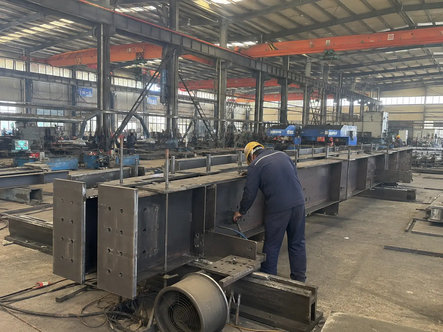 Steel beam build up process in steel fabrication factory with worker assembling welded components