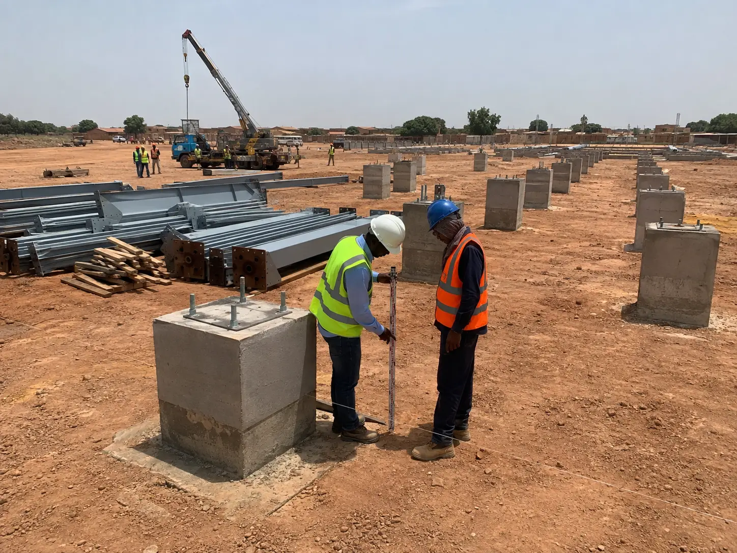 Steel warehouse foundation interface inspection with anchor bolts and steel columns prepared for installation