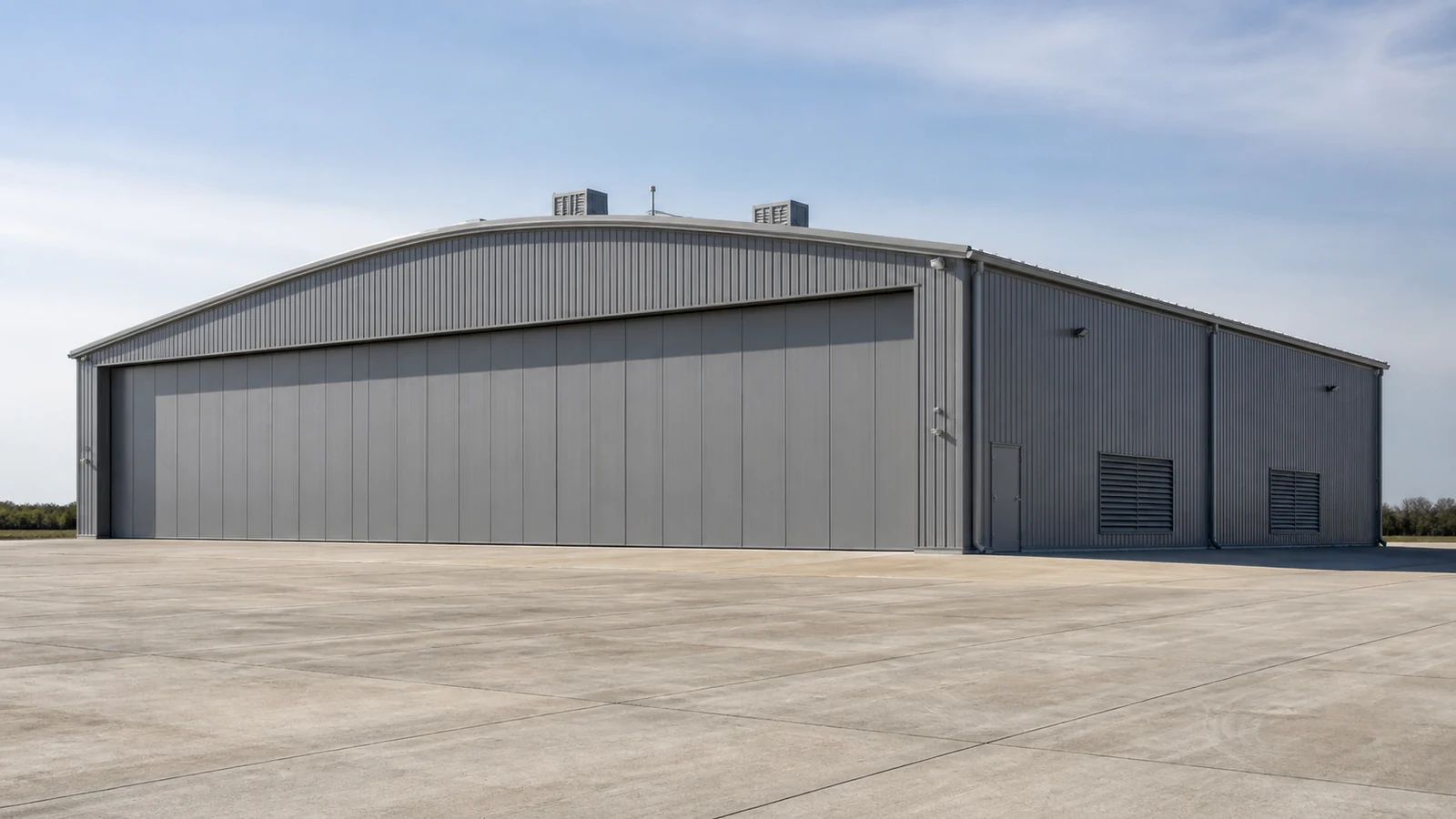 Completed aircraft maintenance hangar with protected louvers and large closed hangar doors.
