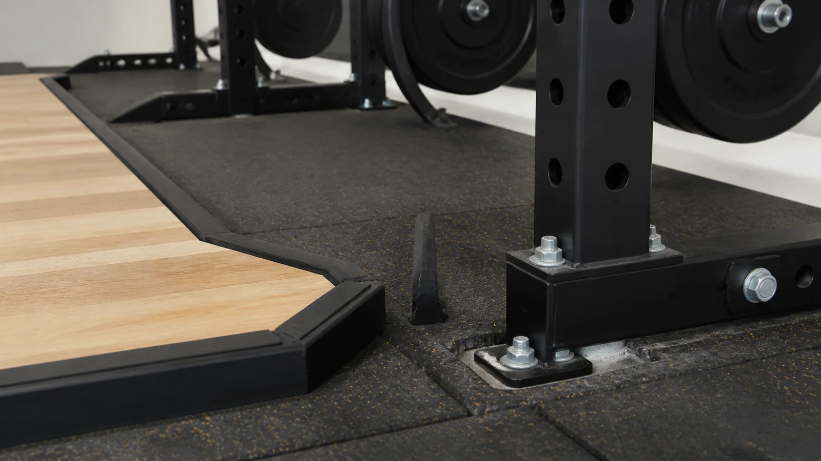 Close view of gym equipment anchors fixed into a finished concrete slab beside a steel column.