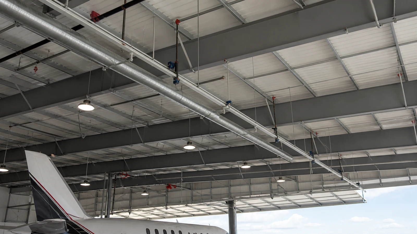 Hangar ceiling shows coordinated fall rail, lighting, services, and door structure
