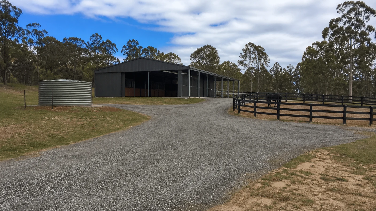 All-weather access road and water point serve a steel horse barn and holding paddock