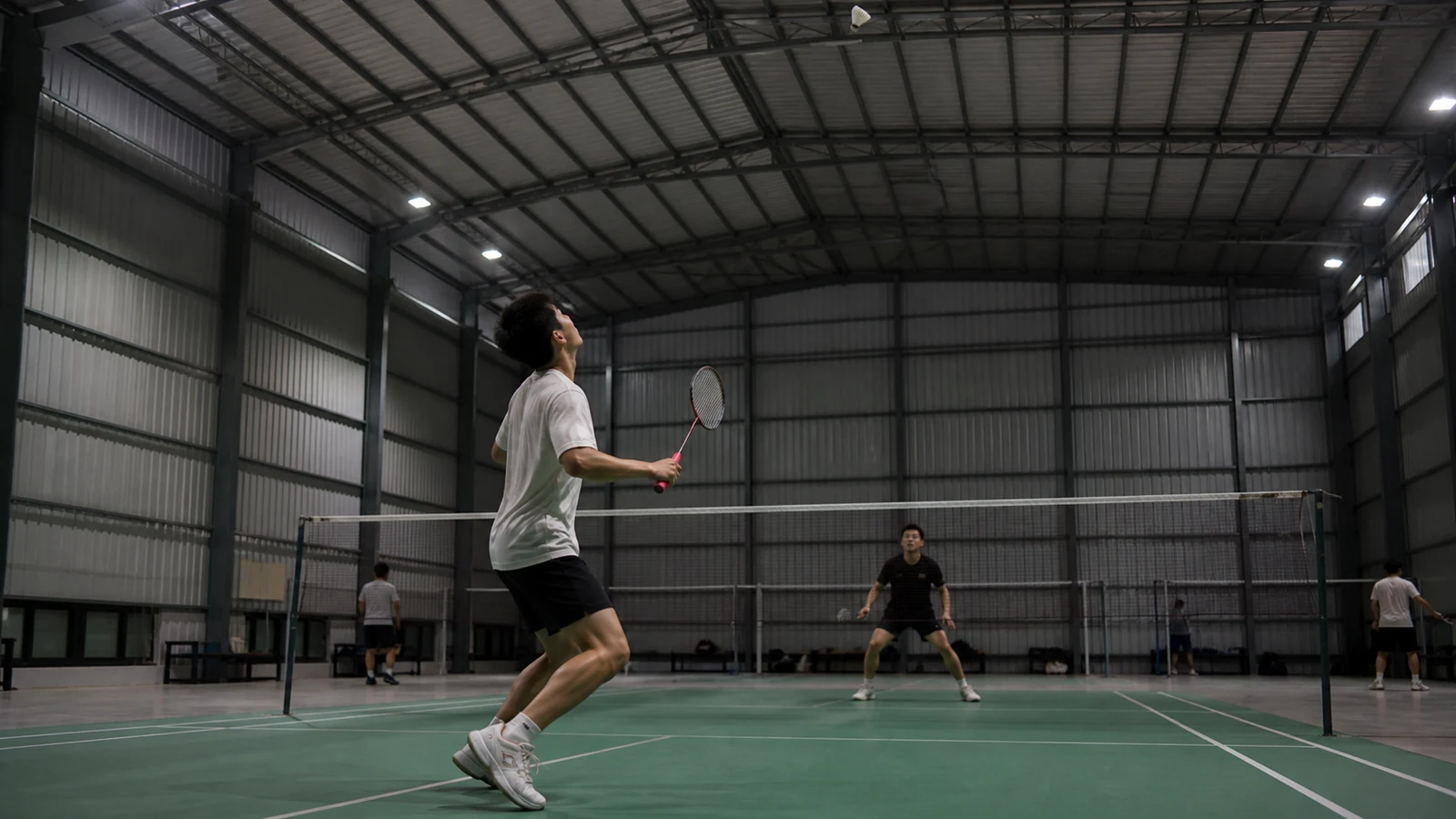 Badminton players train under shielded fixtures arranged away from critical sightlines