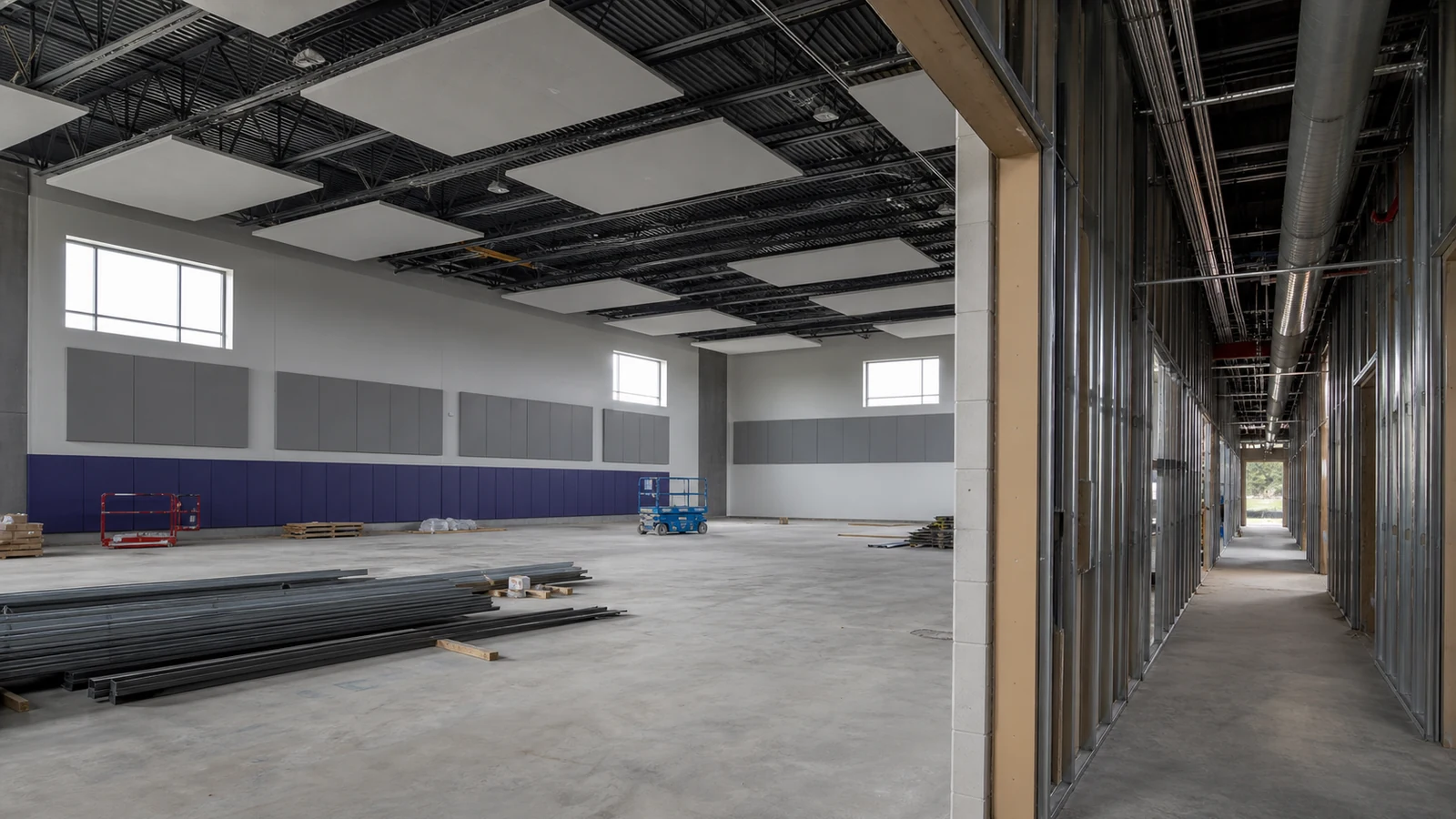 Steel school gym receives durable acoustic wall and roof treatments during construction.