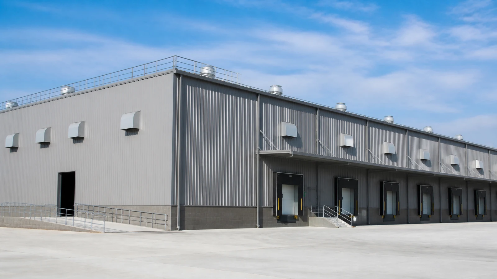 Completed steel warehouse with ridge ventilators and protected wall louvers.